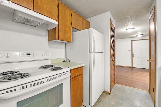 kitchen with white appliances, light wood-type flooring, and a textured ceiling