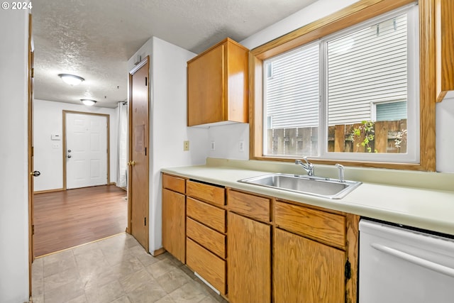 kitchen with dishwasher, light wood-type flooring, a textured ceiling, and sink