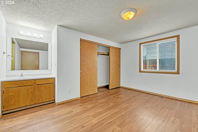 unfurnished bedroom featuring a closet, light wood-type flooring, and a textured ceiling