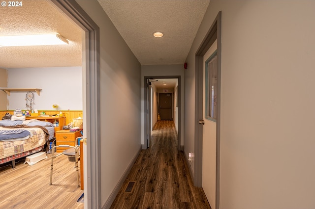 corridor with a textured ceiling and dark hardwood / wood-style floors