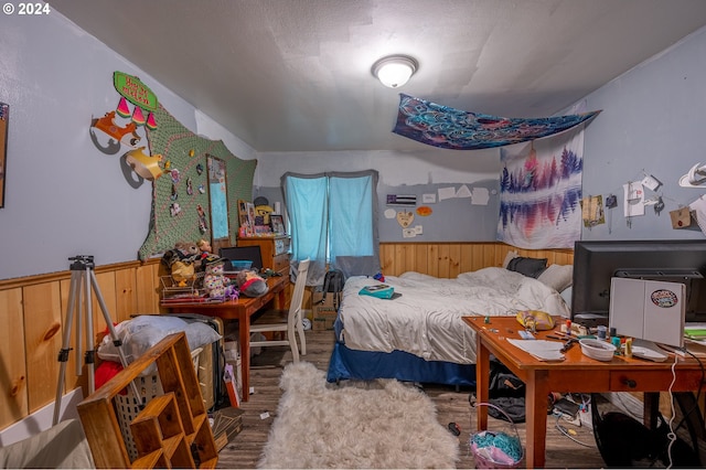 bedroom with hardwood / wood-style flooring and wooden walls