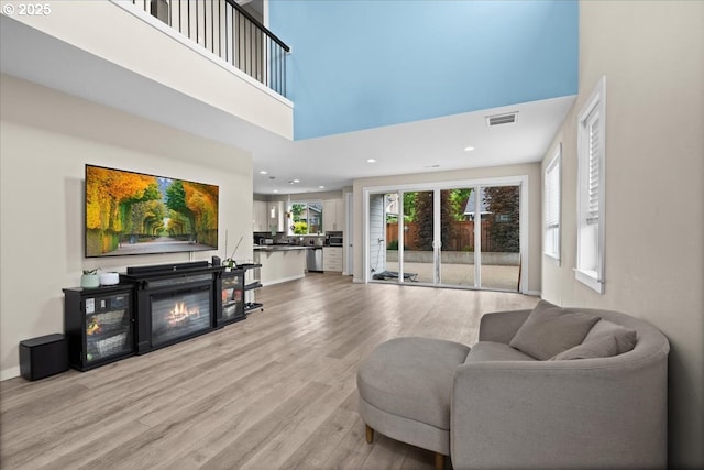2410 S Heather St, Cornelius, OR 97113 - living room with light wood-style floors, a towering ceiling, a glass covered fireplace, recessed lighting, and baseboards