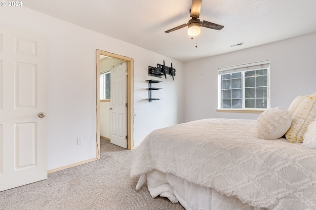 bedroom with multiple windows, light colored carpet, and ceiling fan