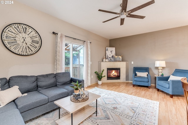 living room featuring ceiling fan, hardwood / wood-style floors, and a tile fireplace