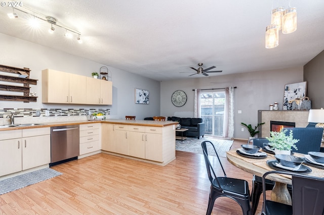 kitchen with sink, dishwasher, kitchen peninsula, pendant lighting, and light hardwood / wood-style floors