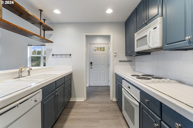 kitchen with tile counters, open shelves, white appliances, and light wood-style flooring