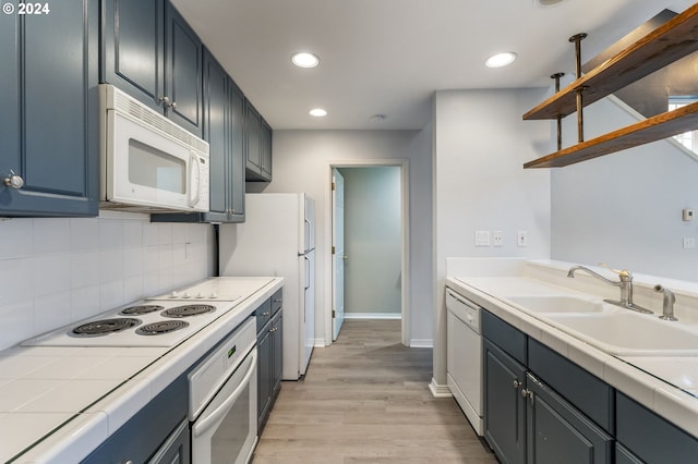 kitchen featuring open shelves, a sink, white appliances, light wood-style flooring, and backsplash