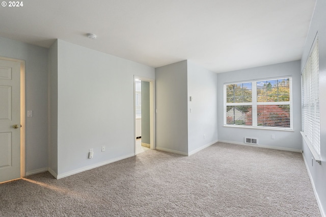 empty room with light colored carpet, baseboards, and visible vents