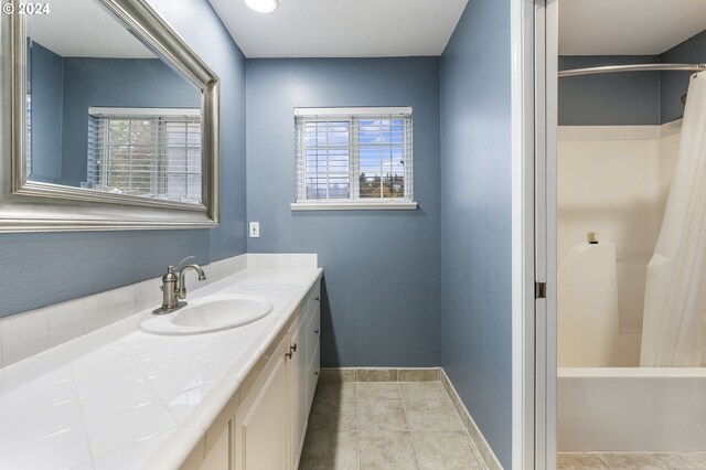 full bath with plenty of natural light, baseboards, tile patterned floors, and vanity