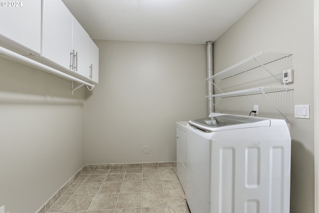laundry area featuring separate washer and dryer, cabinet space, and baseboards