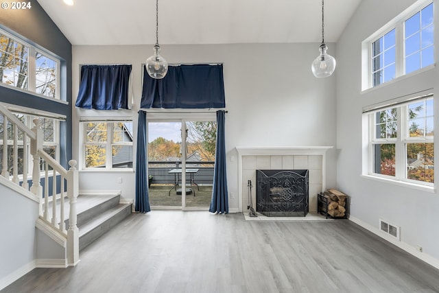 unfurnished living room featuring visible vents, plenty of natural light, wood finished floors, and a tile fireplace