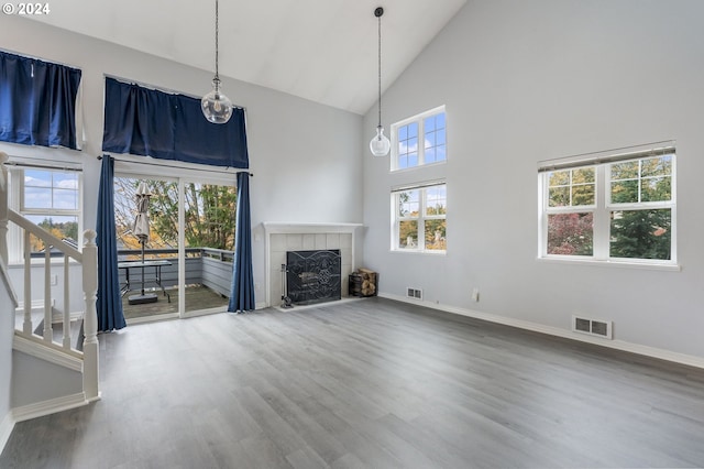 unfurnished living room with visible vents, baseboards, a fireplace, and high vaulted ceiling