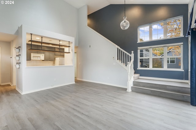 unfurnished living room featuring light hardwood / wood-style floors and high vaulted ceiling