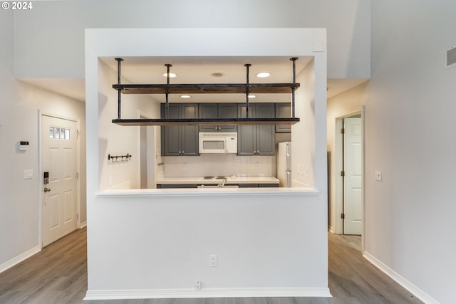 kitchen featuring white appliances, baseboards, decorative backsplash, and wood finished floors