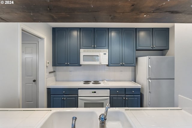 kitchen with tile counters, decorative backsplash, white appliances, and blue cabinetry