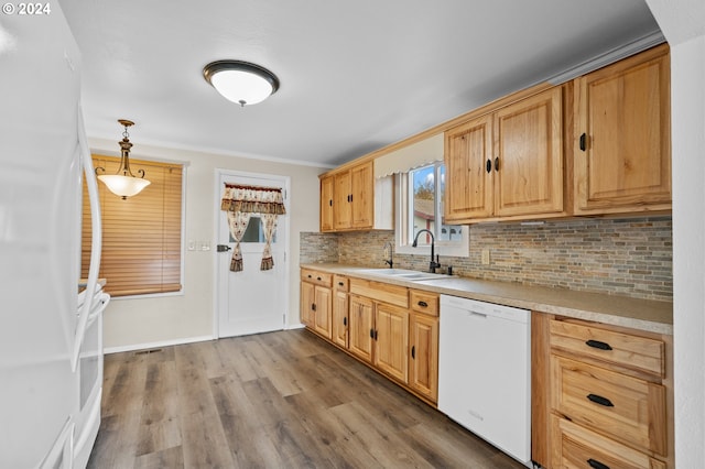 kitchen featuring crown molding, pendant lighting, sink, hardwood / wood-style floors, and white appliances