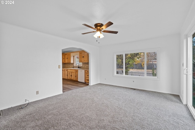 unfurnished living room with sink, ceiling fan, and dark carpet