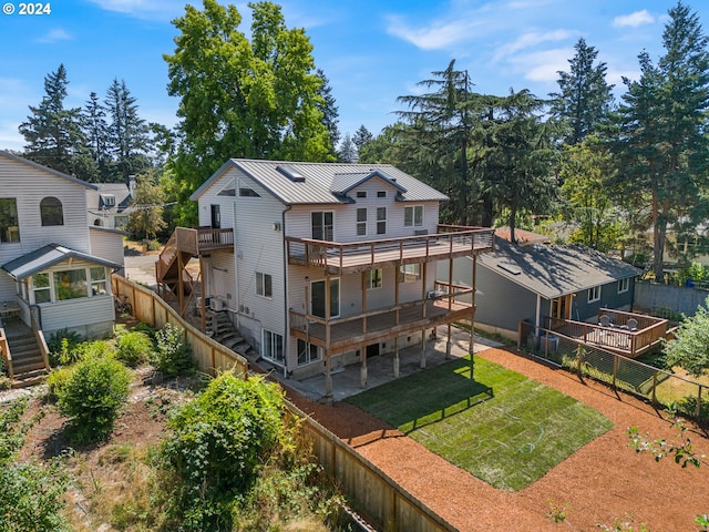 back of house with a yard, a wooden deck, and a patio area