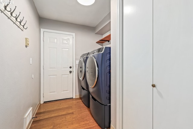 laundry room featuring light wood-type flooring and washer and clothes dryer