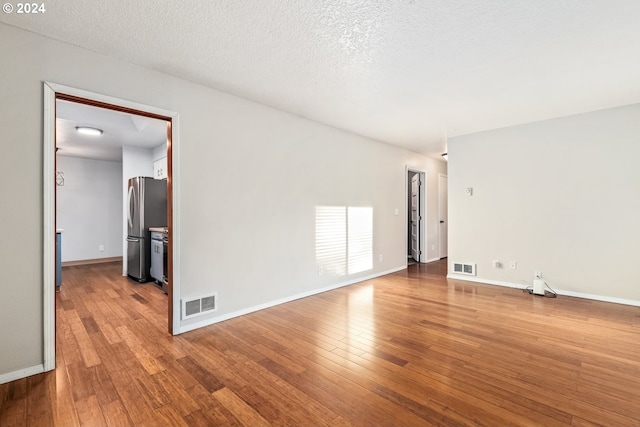 spare room featuring hardwood / wood-style floors and a textured ceiling