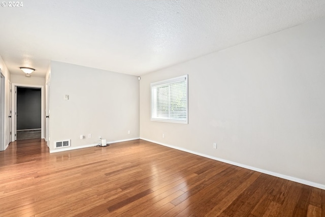 spare room with a textured ceiling and hardwood / wood-style floors