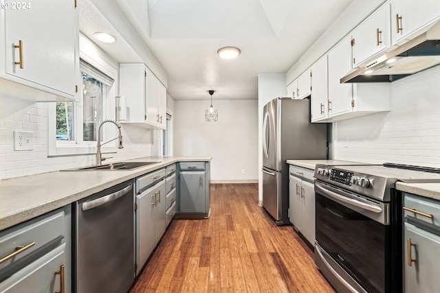 kitchen with light wood-type flooring, sink, decorative backsplash, appliances with stainless steel finishes, and white cabinets