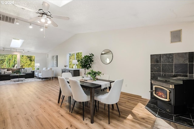 dining space with ceiling fan, light wood-type flooring, plenty of natural light, and a wood stove