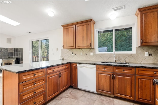 kitchen featuring dark stone countertops, white dishwasher, sink, and kitchen peninsula