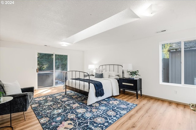 bedroom featuring multiple windows, access to outside, and hardwood / wood-style floors