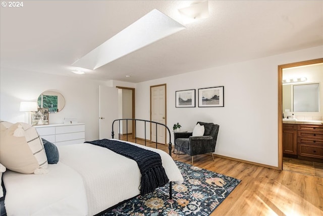 bedroom with light wood-type flooring, connected bathroom, and sink