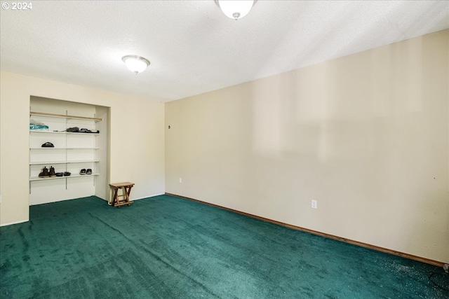 unfurnished room featuring dark carpet and a textured ceiling