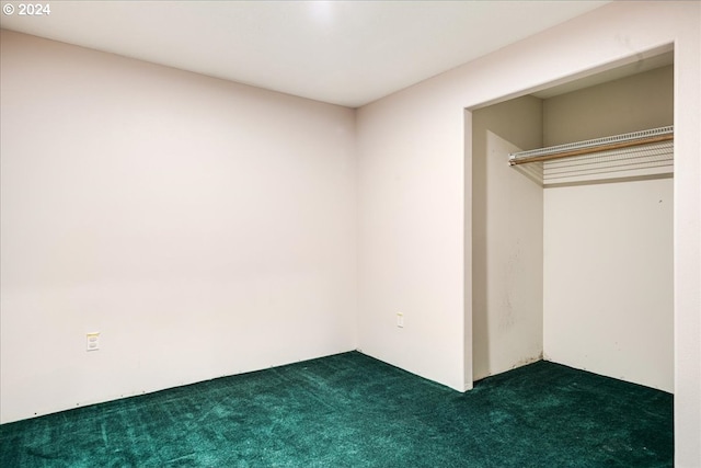 unfurnished bedroom featuring dark carpet and a closet