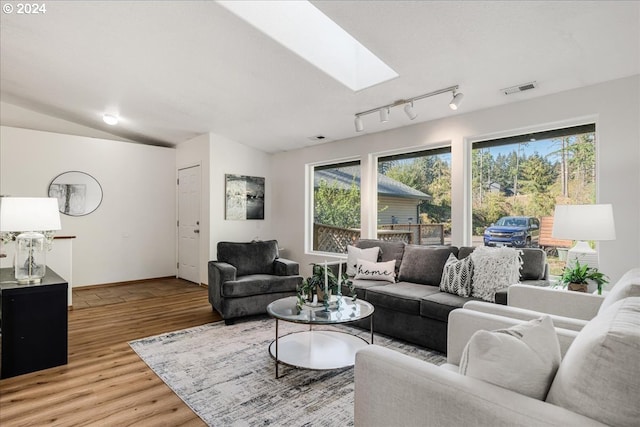 living room featuring lofted ceiling with skylight, light hardwood / wood-style flooring, and a wealth of natural light