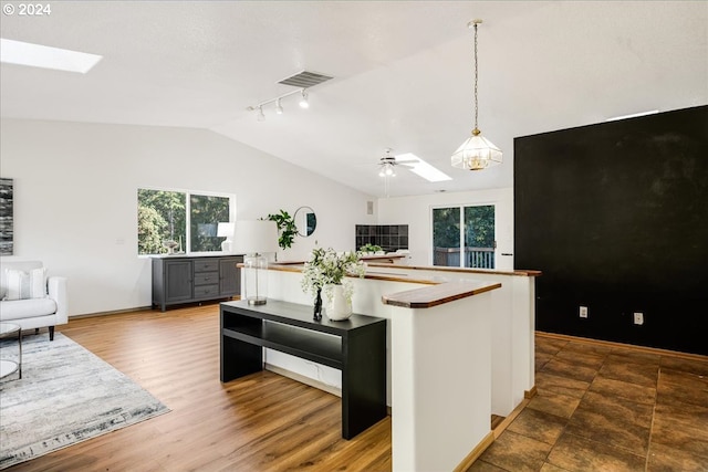 kitchen with wood-type flooring, decorative light fixtures, rail lighting, lofted ceiling with skylight, and ceiling fan with notable chandelier