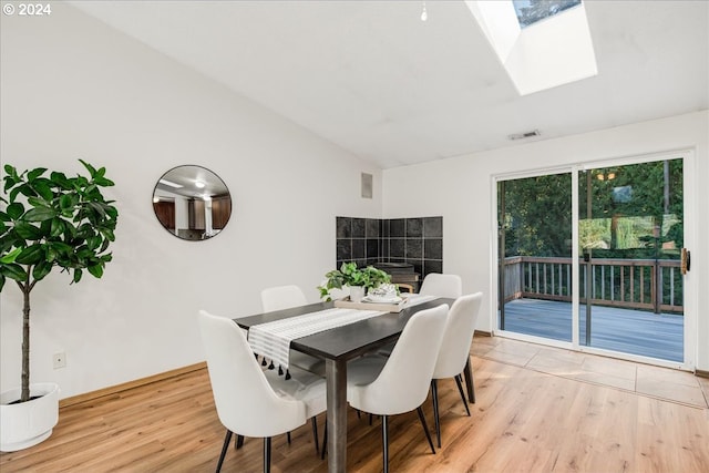 dining area with light hardwood / wood-style flooring and lofted ceiling with skylight