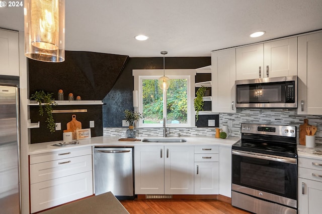 7184 Battle Creek Rd, Salem, OR 97317 - kitchen featuring appliances with stainless steel finishes, open shelves, a sink, light wood-style flooring, and backsplash