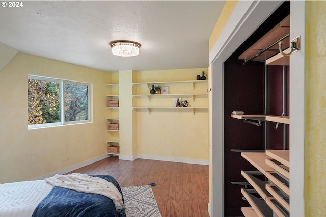 bedroom featuring vaulted ceiling, light hardwood / wood-style flooring, and a textured ceiling