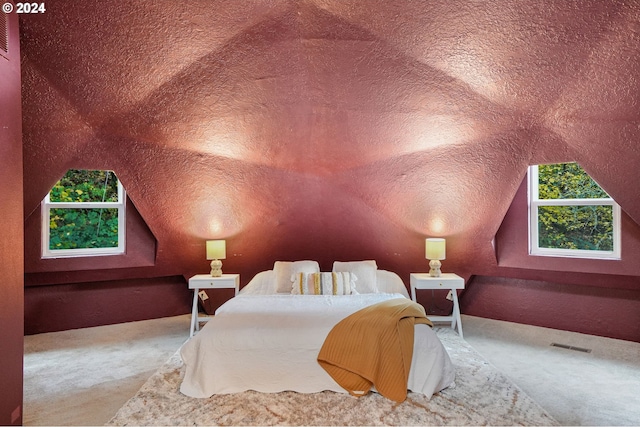 carpeted bedroom featuring a textured ceiling and lofted ceiling