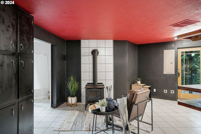 tiled living room featuring a wood stove and a textured ceiling