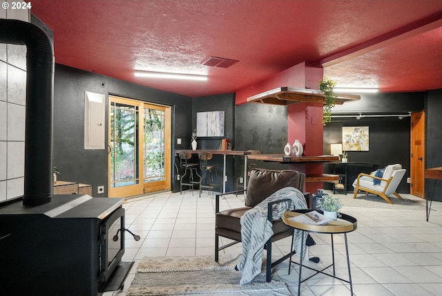 interior space featuring light tile patterned flooring, a wood stove, a textured ceiling, and bar