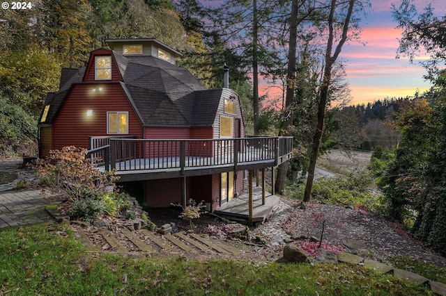 back house at dusk featuring a deck