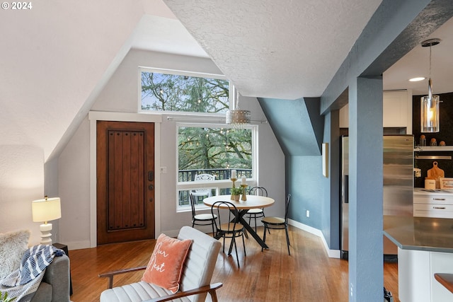 dining space with a textured ceiling and light hardwood / wood-style flooring