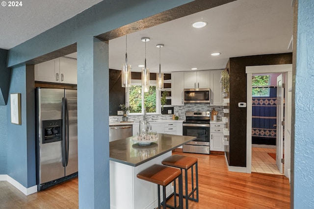 kitchen with light wood-type flooring, stainless steel appliances, and white cabinetry