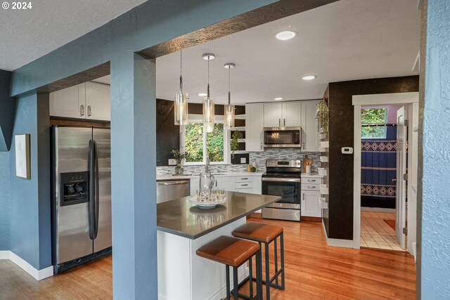 7184 Battle Creek Rd, Salem, OR 97317 - kitchen featuring stainless steel appliances, light wood finished floors, tasteful backsplash, white cabinets, and recessed lighting