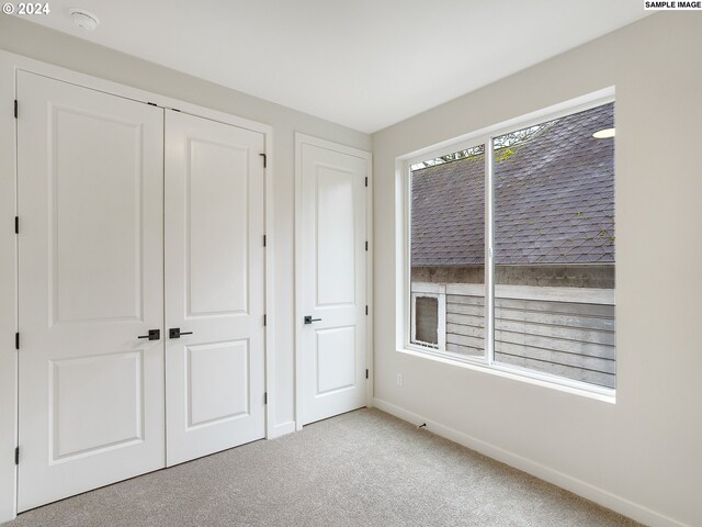 unfurnished bedroom featuring a closet and light colored carpet