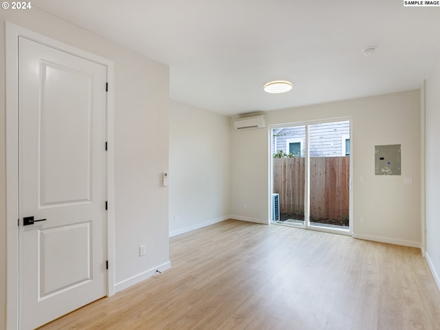 empty room with an AC wall unit and light hardwood / wood-style floors