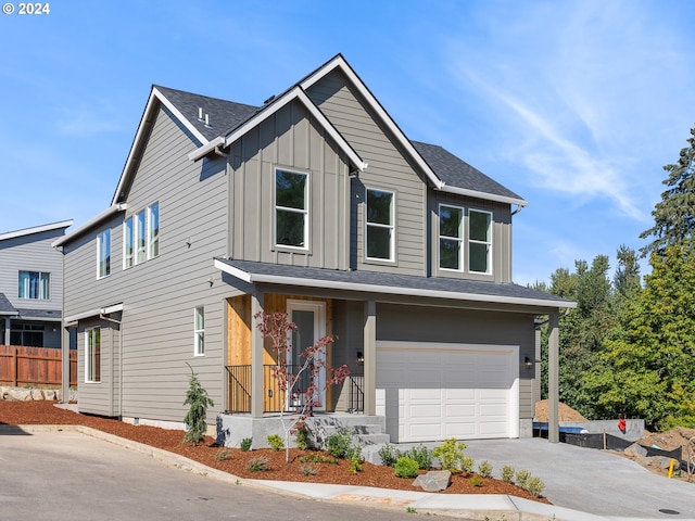 view of front of house with board and batten siding, concrete driveway, a garage, and fence