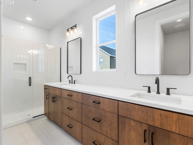 full bathroom featuring a stall shower, double vanity, tile patterned flooring, and a sink
