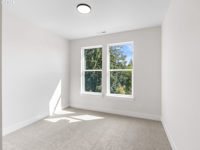 spare room with light colored carpet, visible vents, and baseboards
