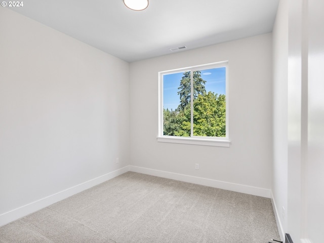 unfurnished room with baseboards, light colored carpet, and visible vents